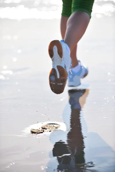 Voeten van jonge vrouw joggen op het strand — Stockfoto