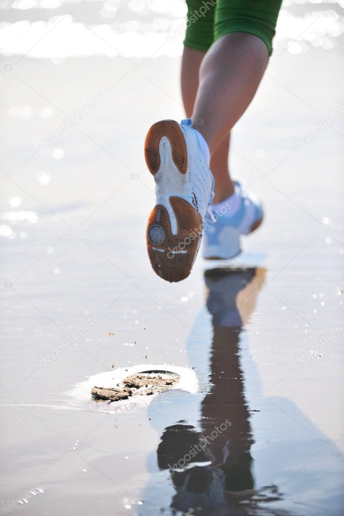 Feet of young woman jogging on the beach