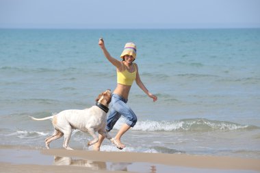 genç kadın köpeğiyle kumsalda oynarken