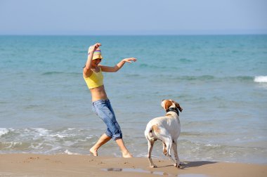 genç kadın köpeğiyle kumsalda oynarken