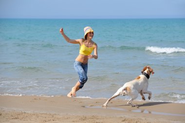 genç kadın köpeğiyle kumsalda oynarken