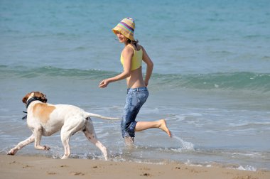 genç kadın köpeğiyle kumsalda oynarken