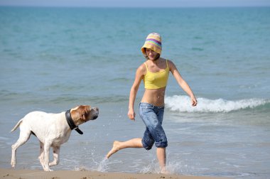 genç kadın köpeğiyle kumsalda oynarken