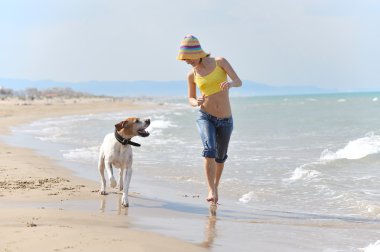 genç kadın köpeğiyle kumsalda oynarken