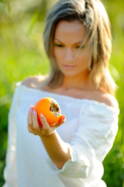 Young woman holding persimmon — Stock Photo, Image