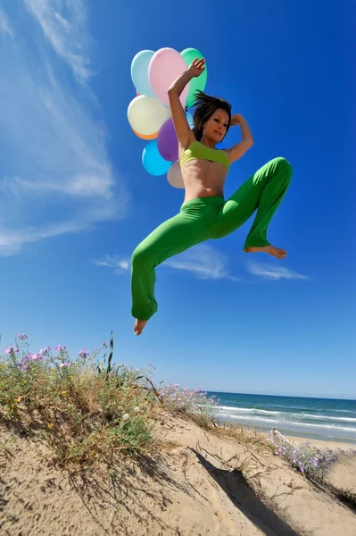 Junge Frau mit bunten Luftballons am Strand — Stockfoto
