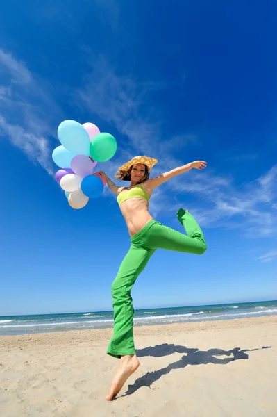 Ung kvinna med färgglada ballonger på stranden — Stockfoto