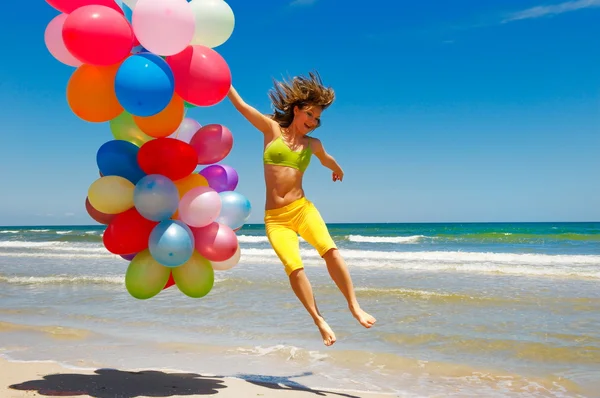 Молодая женщина с разноцветными воздушными шарами на пляже — стоковое фото