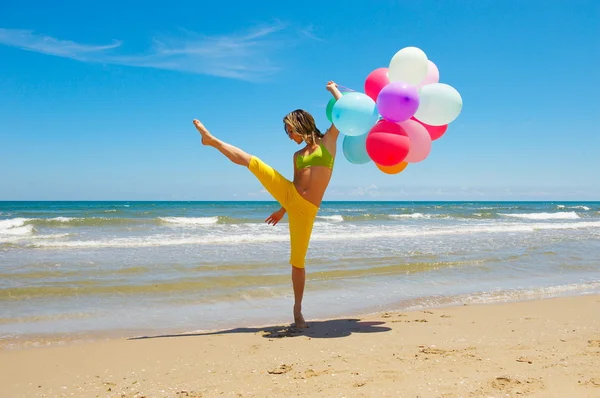 Jeune femme avec des ballons colorés sur la plage — Photo