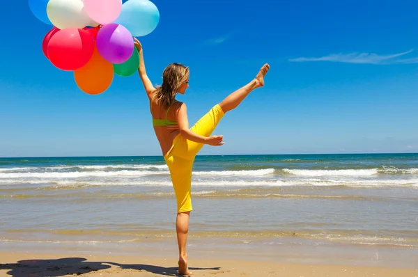 Jeune femme avec des ballons colorés sur la plage — Photo
