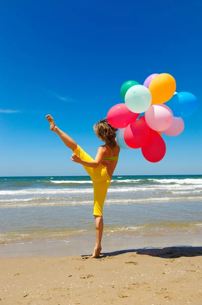 Fiatal nő, színes léggömbök a strandon — Stock Fotó