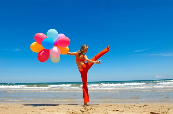 Jonge vrouw met kleurrijke ballonnen op het strand — Stockfoto