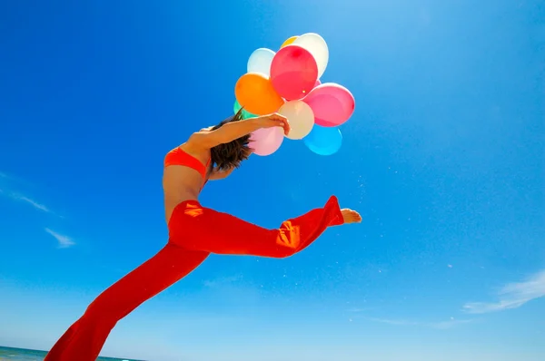 Mladá žena s barevnými balónky na pláži — Stock fotografie