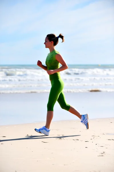 Junge Frau joggt am Strand — Stockfoto