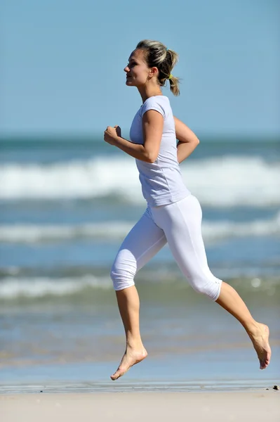 Молода жінка біжить на пляжі — стокове фото