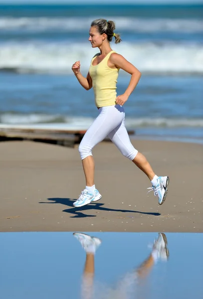 Mujer joven corriendo en la playa — Foto de Stock