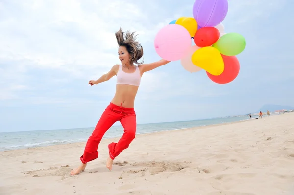 Νεαρή γυναίκα με πολύχρωμα μπαλόνια για την παραλία — Φωτογραφία Αρχείου
