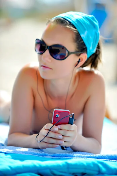 Jonge vrouw op het strand luisteren muziek — Stockfoto