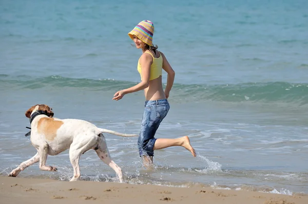 stock image Young woman playing with her dog on the beach
