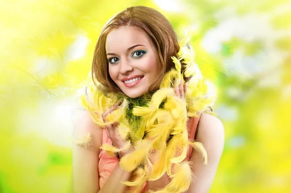 Easter picture of young woman with yellow feathers against green background — Stock Photo, Image