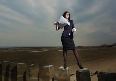 Business lady standing on the beach, on a background cloudy sky. clipart