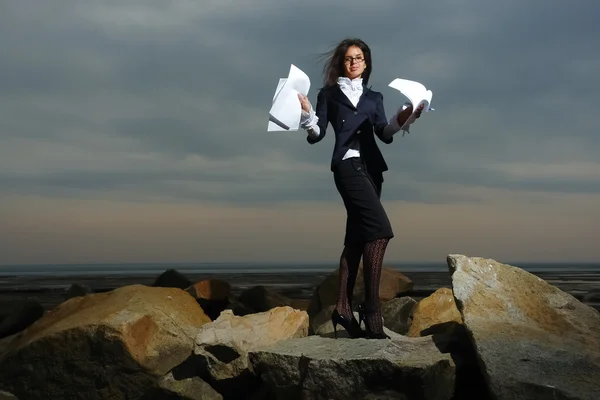 Business ladies standing on rocks by the sea, against the backdrop of a cloudy sky. — Stock Photo, Image