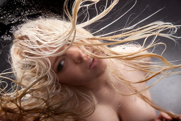 Blond tjej i en våt glas. — Stockfoto