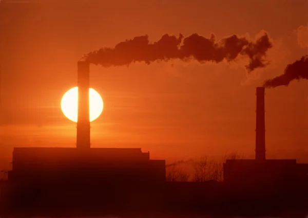 Chimneys and smoke against the setting sun. — Stock Photo, Image