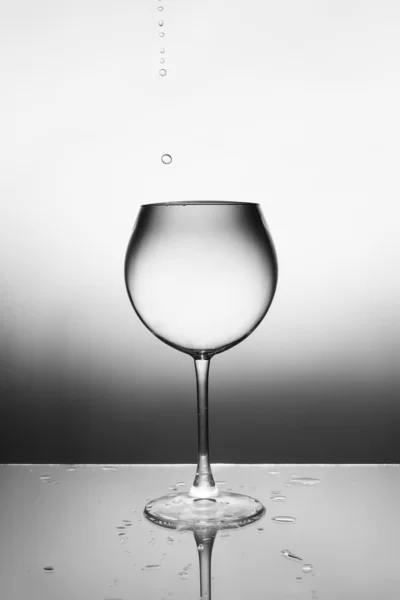 Ett glas klar vätska och en droppe falla i det. — Stockfoto