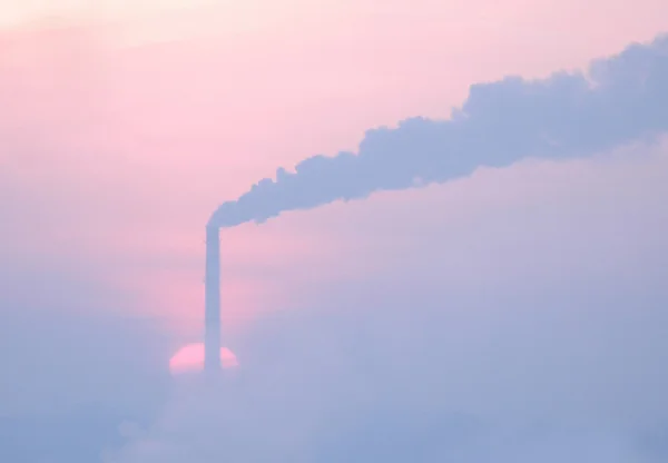 stock image The rising sun over a steaming pipe.