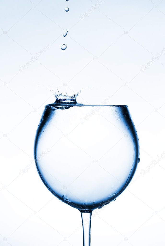 A glass of clear liquid and a drop falling into it.