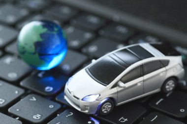 Glass globe and toy car over keyboard clipart