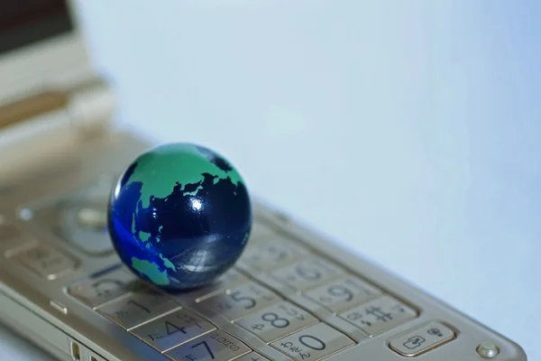 Glass globe over cellphone — Stock Photo, Image