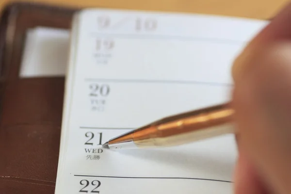 Man filling out monthly planner on the table — Stock Photo, Image