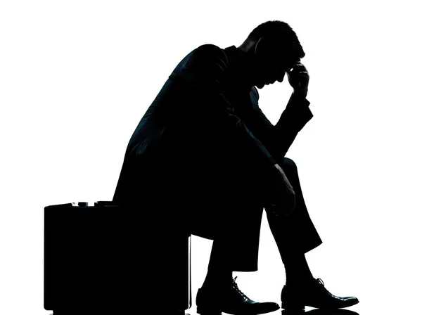 Ein Geschäftsmann sitzt auf einem Koffer müde Verzweiflung Silhouette — Stockfoto