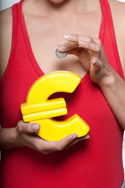 Detail shot of woman with small savings and Euro shaped piggyban — Stock Photo, Image