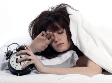 Woman in bed awakening tired holding alarm clock clipart
