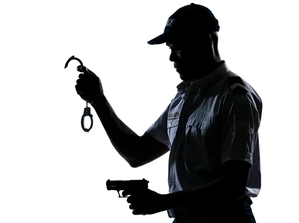 Полицейский держит наручники и пистолет. — стоковое фото