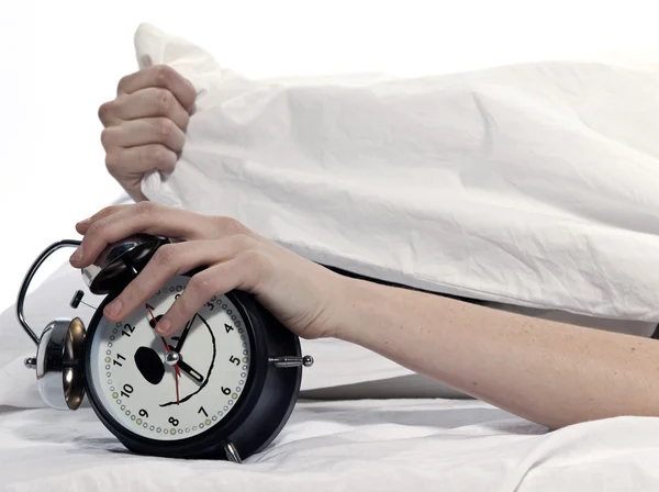 Frau im Bett wacht müde auf und hält Wecker — Stockfoto