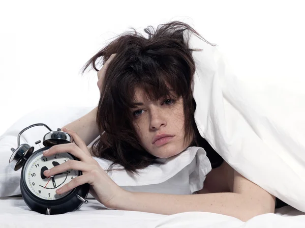 Kvinnan i sängen uppvaknande trött håller väckarklocka — Stockfoto