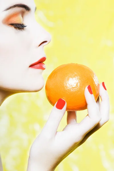 Frauenporträt, das an einer orangen Mandarinenfrucht riecht — Stockfoto