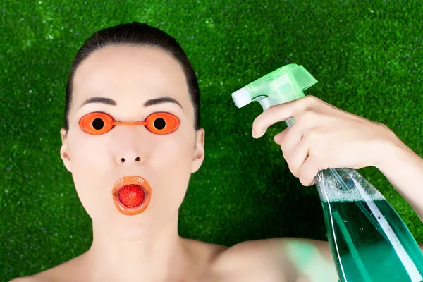 Žena nosí brýle opalovací lůžko s jahodou v ústech a s — Stock fotografie