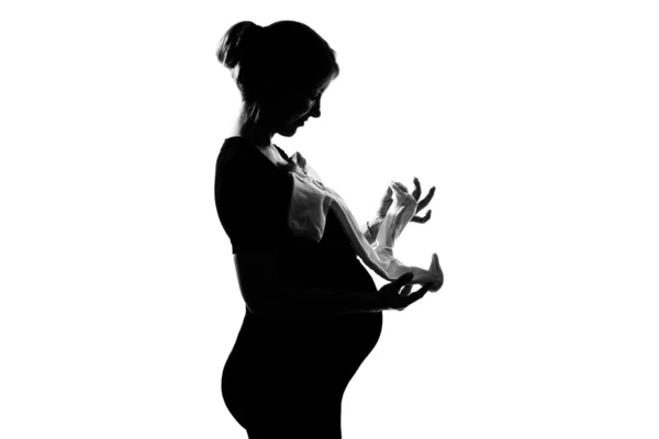 Pregnant woman holding baby clothes — Stock Photo, Image