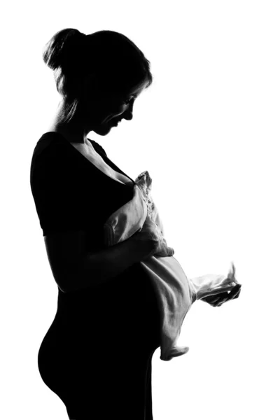 Mulher grávida segurando roupas de bebê — Fotografia de Stock