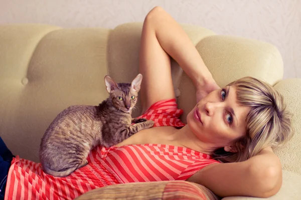 Donna con gatto sdraiato su un divano — Foto Stock