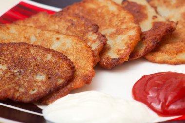 Potato pancake with sour cream and ketchup clipart