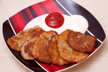 Potato pancake with sour cream and ketchup clipart