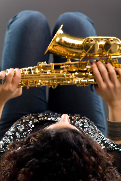 Девушка с саксофоном на сером фоне
