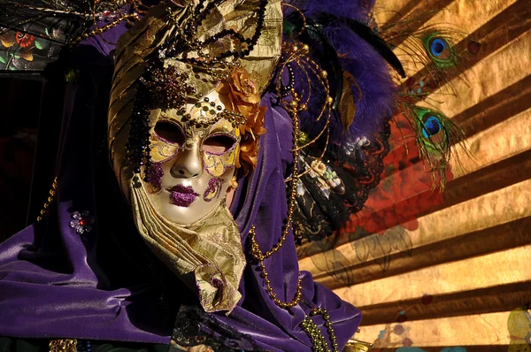 Máscara Veneciana vestida de violeta con Abanico dorado Fotos de stock libres de derechos