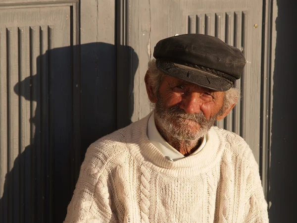 Пожилой рыбак перед дверью на греческом острове — стоковое фото